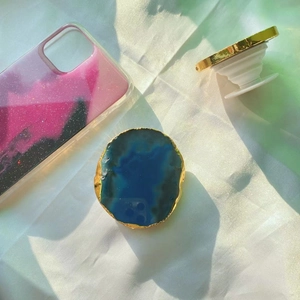 Blue agate phone grip with gold trim on glitter case, 45-degree angle view