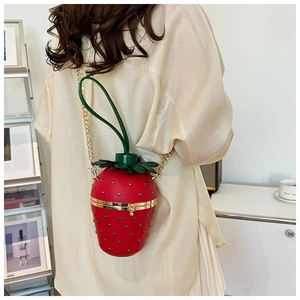 Detail of strawberry shaped crossbody bag with gold chain strap and rivet seeds