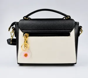 Close-up of a pink floral resin keychain pendant on a monochrome faux leather handbag