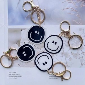 Smiling face keychains set with gold metal rings and acrylic charms on a lifestyle background