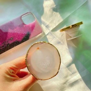 Detail view of natural agate stone phone grip with gold electroplated edges on a pink case