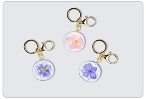 Close-up of resin keychains with real dried flowers in pink, purple, and blue hues
