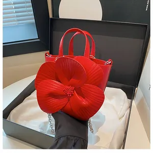 Detailed view of red camellia bucket bag with 3D petals in a black gift box