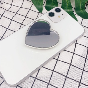 Detailed macro view of heart-shaped diamond makeup mirror phone grip on a white smartphone