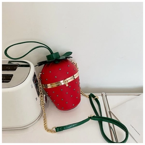 Detail of strawberry-shaped crossbody bag with red lychee leather and gold chain strap