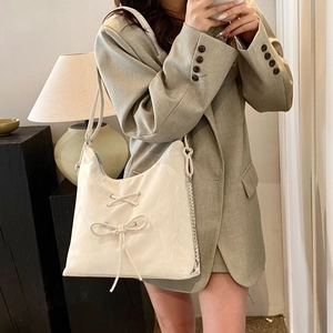 Detail of white textured shoulder bag featuring chic ribbon bow and silver metal chain