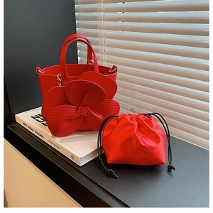 Detailed macro view of 3D floral petal design on red leather bucket bag with inner pouch
