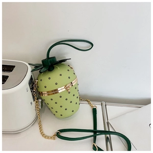 Macro shot of creative strawberry-shaped handbag with green leaves and gold chain strap