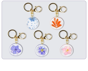 Macro view of five assorted dried flower resin keychains with golden metal rings