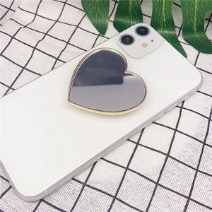 Macro detail of a heart-shaped makeup mirror phone stand in gold and silver finish