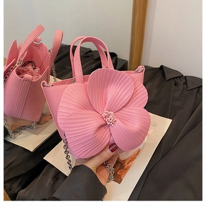 Detailed view of 3D camellia floral petals and pearl center on the pink bucket bag