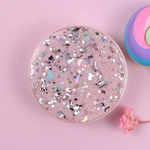 Macro detail of round pink glitter phone socket with holographic stars and moon sequins