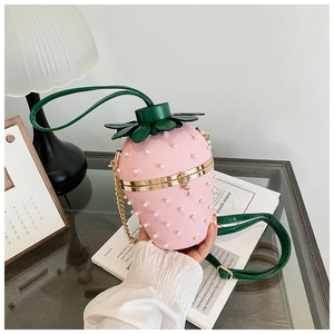 Detailed view of pink strawberry bucket bag with pearl accents and gold metal chain strap