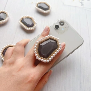 Detail of grey gem phone grip with golden rhinestones and white pearl border