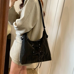 Detail of a black hobo bag with ribbon bows and silver metal chain strap detail