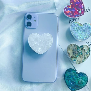 Macro shot of heart-shaped shell texture phone grip on a purple smartphone back