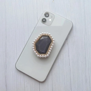Detailed view of luxury phone grip featuring grey gem, rhinestones and pearls on phone