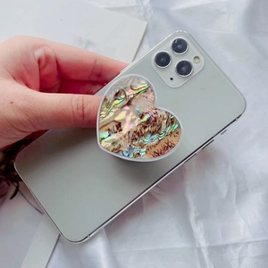 Heart-shaped expanding phone grip with iridescent natural abalone shell on a smartphone