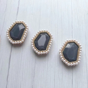 Close-up of three dark gray gemstone phone grips with gold frames and pearl borders
