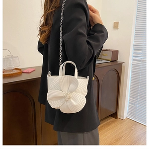 Detailed close-up of a white PU handbag featuring a large 3D floral accent and pearl decor