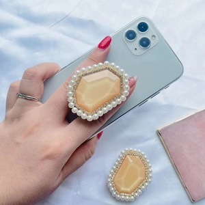 Detail of a gemstone phone socket with pearls and diamonds on a blue smartphone