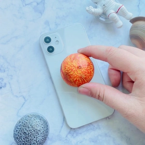 Close-up of a 3D textured planet phone grip stand with realistic orange crater details