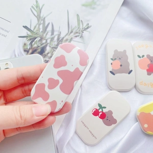 Close-up of cute cartoon bear and cherry Griptok phone stand on a minimalist background