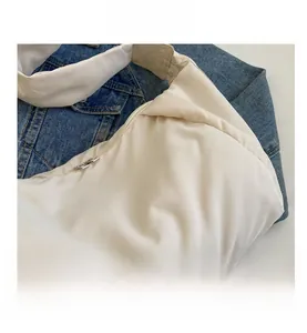 Détail du sac à bandoulière matelassé beige avec fermeture éclair argentée sur denim