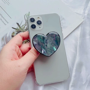 Macro shot of iridescent heart-shaped shell textured grip stand on a smartphone