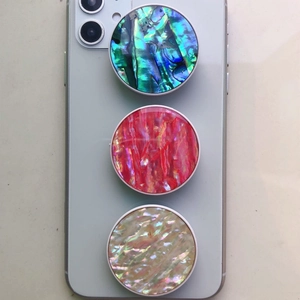 Detailed view of three abalone and pearl shell texture collapsible phone grips