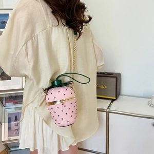 Pink strawberry shaped hard shell bucket bag with green leaf decor and gold chain strap