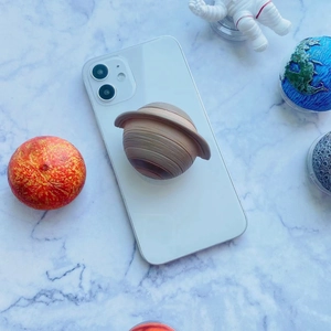Detailed view of a 3D Saturn planet telescopic phone grip on a white smartphone
