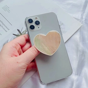 Macro detail of a heart-shaped phone grip with marble pattern on a silver smartphone