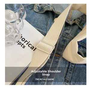 Gros plan sur la bandoulière tissée beige réglable avec boucle argentée de sac
