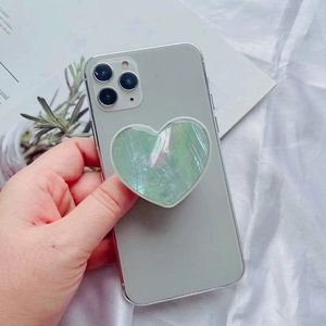 Detail of heart-shaped pearlescent green phone grip with shell texture on a smartphone
