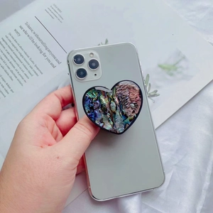 Close-up of heart-shaped iridescent abalone shell phone grip on a smartphone back