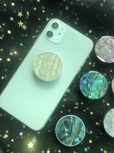 Macro shot of iridescent shell phone grip with expanding stand on white smartphone