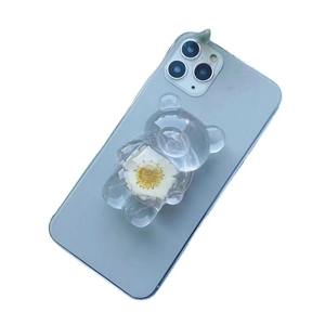 Transparente Bären-Handyhalterung mit weißen Trockenblumen auf einem blauen Smartphone