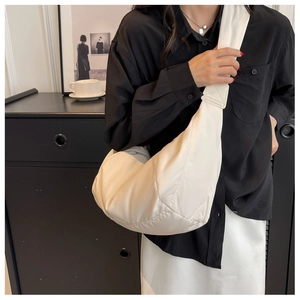 Détail d'un sac bandoulière demi-lune blanc crème avec texture en nylon et coutures renforcées