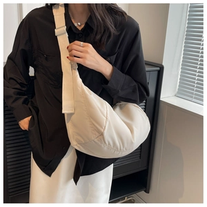 Gros plan sur le sac demi-lune blanc crème avec large bandoulière réglable et boucle en métal