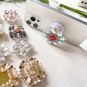 Luxury rhinestone expandable phone grip holder in various colors on a white smartphone