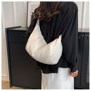Gros plan d'un sac à bandoulière en nylon blanc matelassé porté par un mannequin