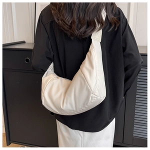 Sac à bandoulière matelassé blanc moderne porté par un mannequin pour un style minimaliste