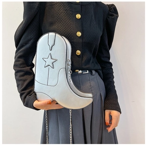 Macro view of silver boot-shaped bag with star stitching and metallic chain strap