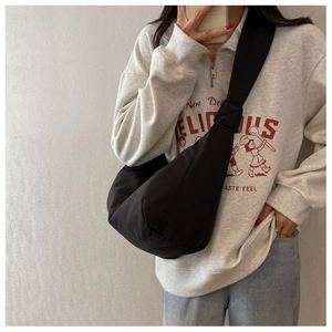 Gros plan d'un sac bandoulière croissant noir porté par un modèle en style streetwear
