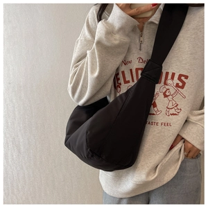 Sac bandoulière demi-lune noir minimaliste porté par un mannequin en tenue décontractée