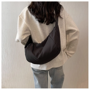 Modèle portant un grand sac croissant noir minimaliste avec une texture en nylon bouffant