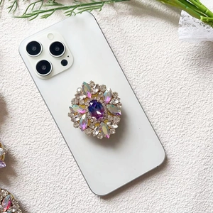 Macro detail of luxury phone grip featuring purple gradient gemstone and diamond accents
