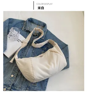 Détail d'un grand sac croissant en nylon blanc cassé avec bandoulière large réglable et zip