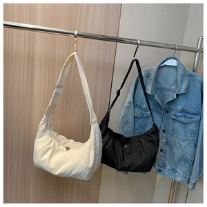 Vue détaillée de sacs croissants matelassés noir et crème suspendus avec une veste en jean
